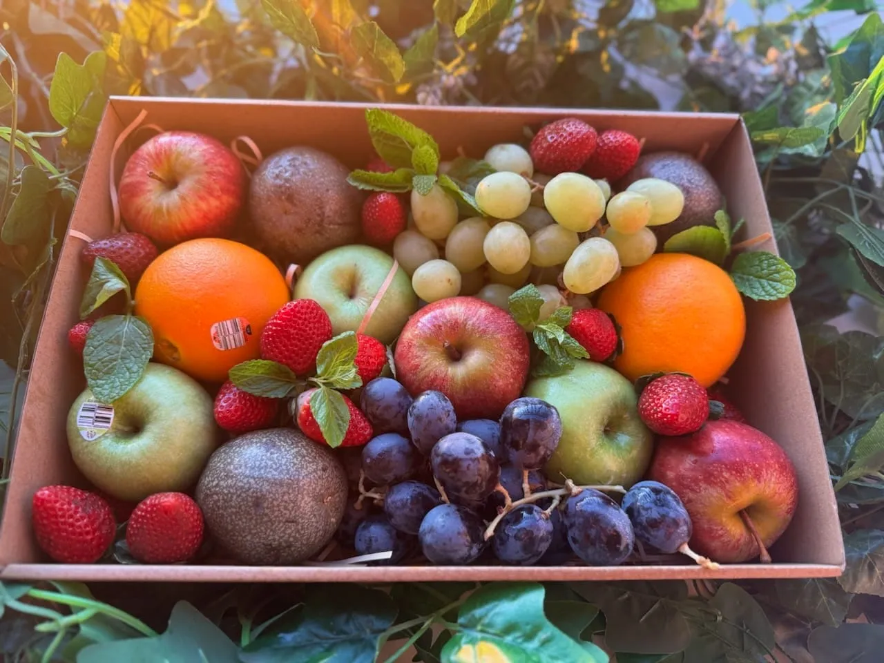 A Natures Basket box packed with apples, oranges, grapes, strawberries and passion fruit